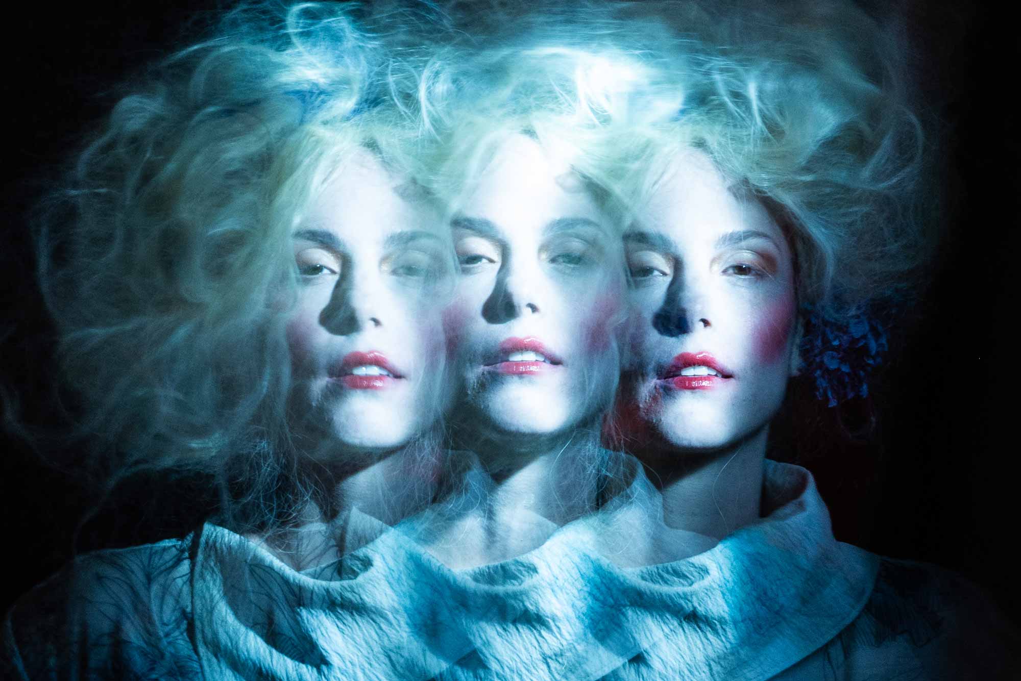 Close-up portrait of a model with three overlapping exposures, creating a blurry, mysterious, and slightly unsettling effect.