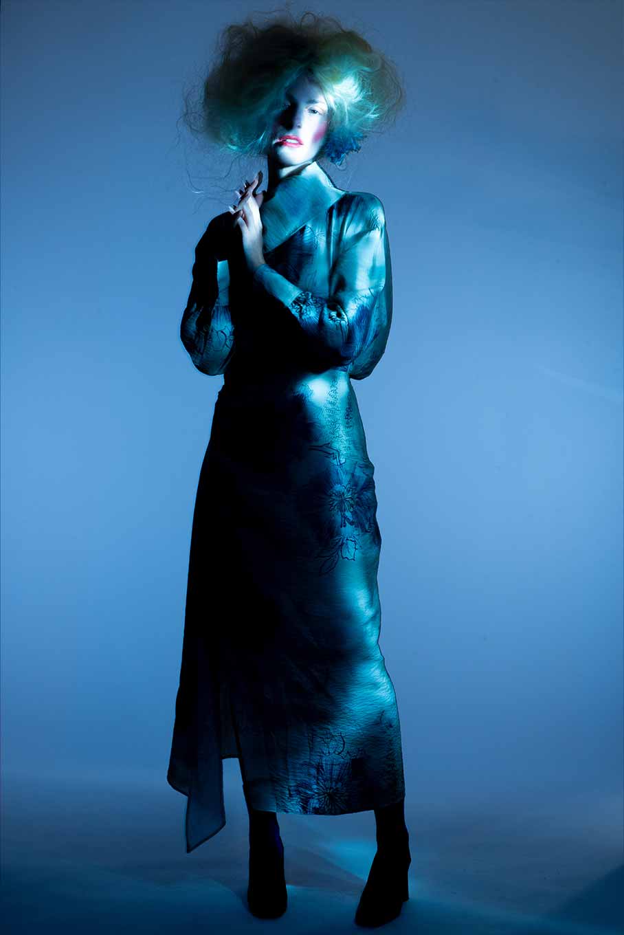 Full-body portrait of a model in a delicate pose, photographed with long exposure and dynamic lighting to create flowing trails of light.